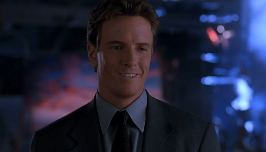 Linden Ashby's Johnny Cage smiling in a grey suit in Mortal Kombat 1995.