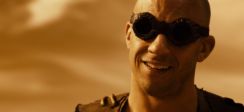 Vin Diesel Riddick smiling in the desert with goggles