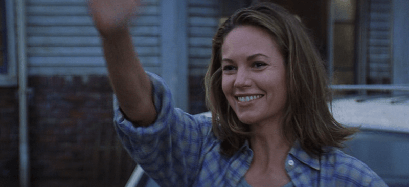 Diane Lane waving and smiling in front of a house