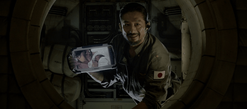 Hiroyuki Sanada holding a tablet showing his family while smiling