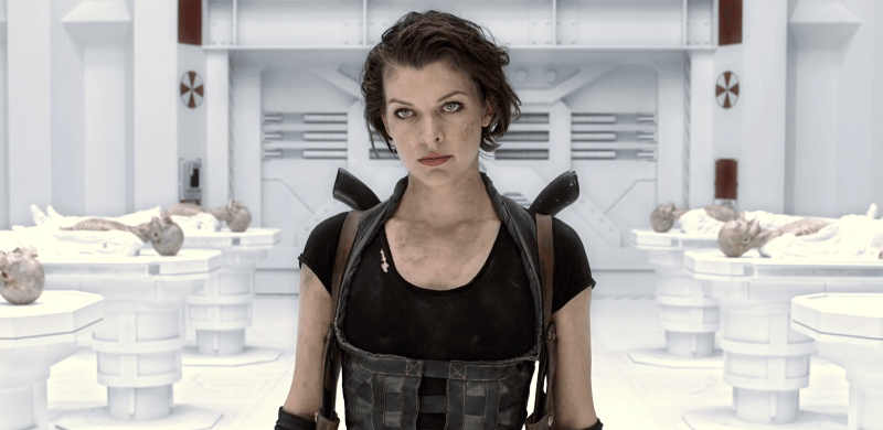 Milla Jovovich in a black outfit in a white Umbrella room with corpses