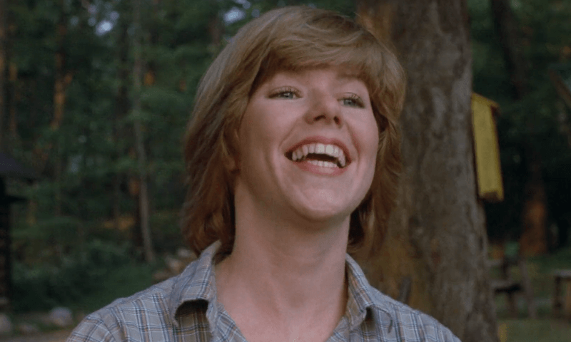 Alice smiling at Camp Crystal Lake in the forest.