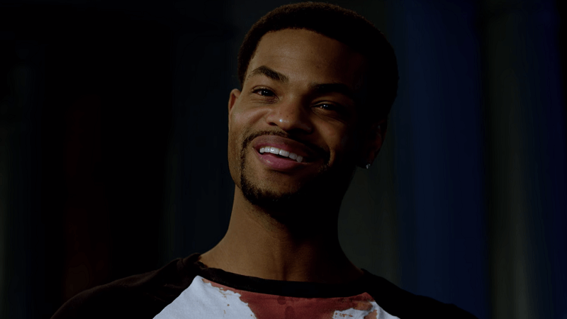 King Bach as John smiling with a huge grin in the dark.