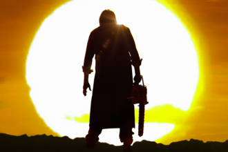 Leatherface standing with a chainsaw in front of the sunset.