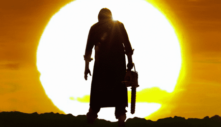 Leatherface standing with a chainsaw in front of the sunset.