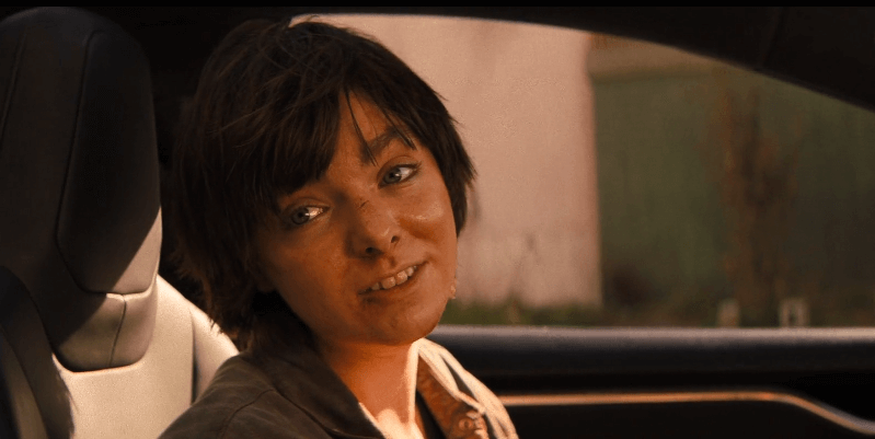 Elsie Fisher as Lila with short hair inside of a car smiling.