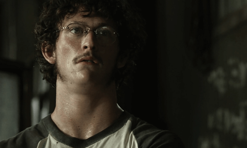 Morgan with curly hair and glasses looking distraught.