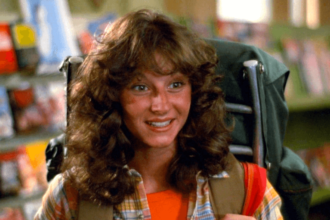 Annie with curly 80s hair wearing a backpack and smiling warmly.
