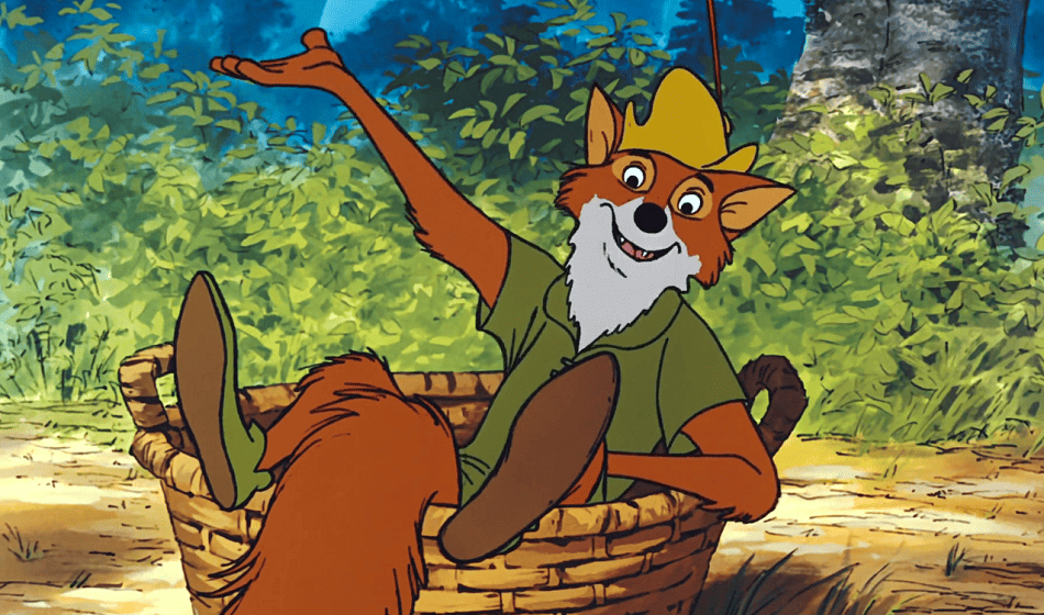 Red Fox Robin Hood sitting inside a basket with his hand in the air looking happy.