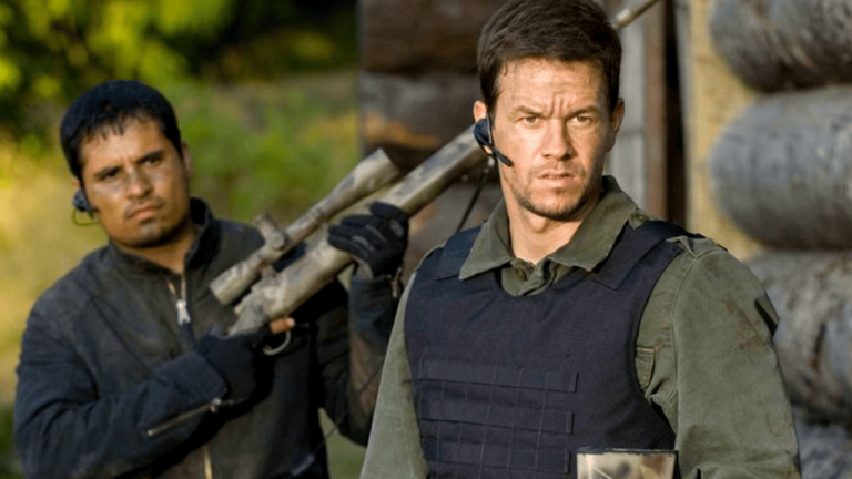 Michael Pena and Mark Wahlberg next to each other with military gear looking ready for war.